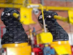 This photo shows two fa,nuc industrial robots, all yellow, protected by two black ATEX covers for explosive environments.